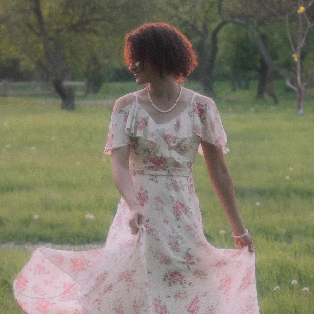 Elisha Antoine twirling her floral dress in a green field